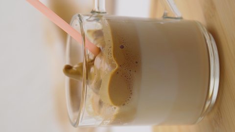 Dalgona Coffee, a trendy fluffy creamy whipped coffee. Korean drink latte espresso with coffee foam. Light background. Vertical video