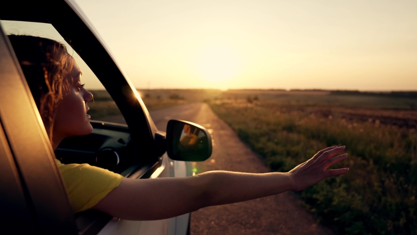 Happy girl in car window. Hair in wind. Girl travels by car. Hand in sun. Windy breeze from car window. Happy girl smiling from car window. Windy breeze in your hair. Hand in the rays of the sun | Shutterstock HD Video #1091738795