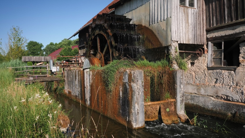 Wooden wheel of old mill turning water. Mill wheel rotates under stream of water