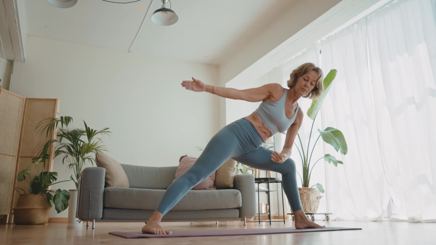 Cinematic storytelling video of a senior old woman practicing yoga and stretching fitness at home. Representation of healthy lifestyle and leisure activities during seniority and the third age | Shutterstock HD Video #1091740883