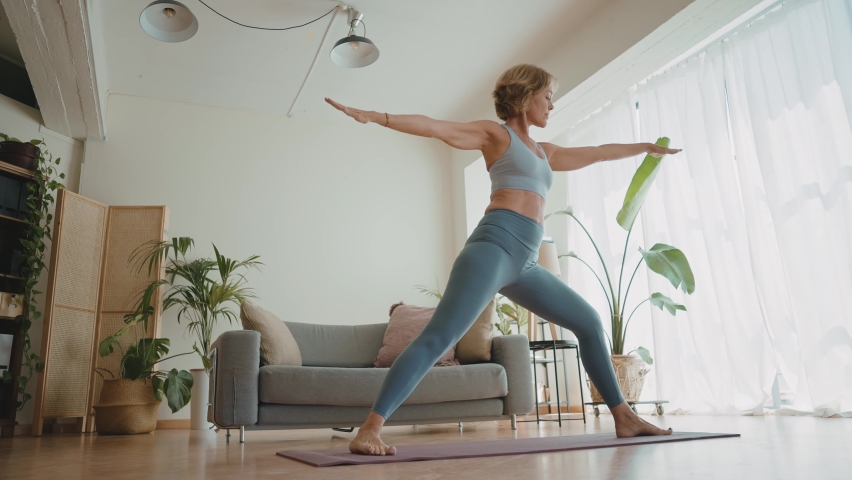 Cinematic storytelling video of a senior old woman practicing yoga and stretching fitness at home. Representation of healthy lifestyle and leisure activities during seniority and the third age | Shutterstock HD Video #1091740885