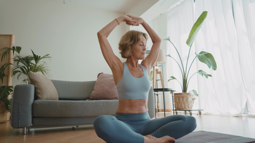 Cinematic storytelling video of a senior old woman practicing yoga and stretching fitness at home. Representation of healthy lifestyle and leisure activities during seniority and the third age | Shutterstock HD Video #1091740887