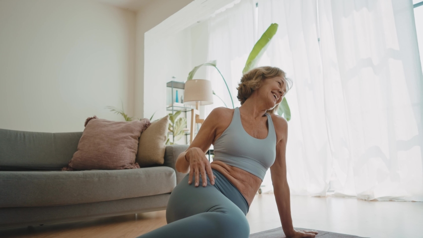 Cinematic storytelling video of a senior old woman practicing yoga and stretching fitness at home. Representation of healthy lifestyle and leisure activities during seniority and the third age | Shutterstock HD Video #1091740891