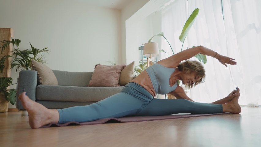 Cinematic storytelling video of a senior old woman practicing yoga and stretching fitness at home. Representation of healthy lifestyle and leisure activities during seniority and the third age | Shutterstock HD Video #1091740893