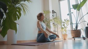 Cinematic storytelling video of a senior old woman practicing yoga and stretching fitness at home. Representation of healthy lifestyle and leisure activities during seniority and the third age
