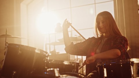 Expressive Drummer Girl Playing Drums in a Loft Music Rehearsal Studio Filled with Light. Rock Band Music Artist Learning a New Drum Solo. Slow Motion Portrait Footage.