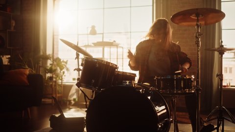 Expressive Drummer Girl Playing Drums in a Loft Music Rehearsal Studio Filled with Light. Young Female Pulls out Her Smartphone to Answer a Social Media Message. Music Artist Learning a New Drum Solo.