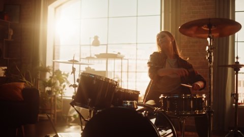 Young Female Playing Drums During a Band Rehearsal in a Loft Studio with Warm Sunlight at Daytime. Drummer Girl Practising Before a Live Concert on Stage. Handheld Shot.