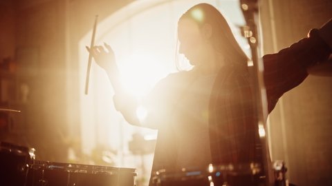 Close Up Portrait of an Expressive Drummer Girl Playing Drums in a Loft Music Rehearsal Studio Filled with Light. Rock Band Music Artist Learning a New Drum Solo.