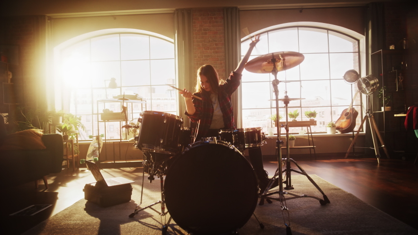 Young Female Playing Drums During a Band Rehearsal in a Loft Studio with Warm Sunlight at Daytime. Drummer Girl Practising Before a Live Concert on Stage. Handheld Shot. Royalty-Free Stock Footage #1091742315