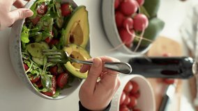 Happy beautiful young woman eating healthy food at home. Salad with Avocado and vegetables in bowl. Healthy food concept. 4k footage. 4k footage. no face. Vertical shoot.