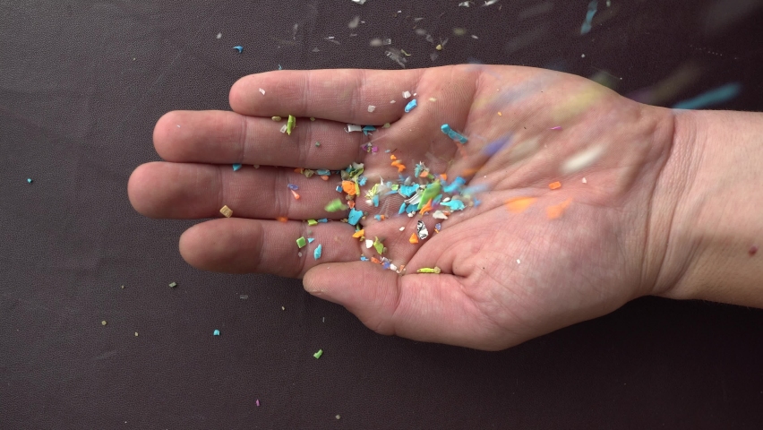 Close-up on micro plastic particles falling in person's hand. Concept for water pollution and global warming. Macro shot on a bunch of microplastics that cannot be recycled | Shutterstock HD Video #1091749151