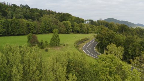 Fleet of sports cars driving on highway in mountains of Czechia, drone.