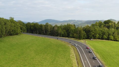 Sports cars fleet driving on bending highway in forests of Czechia.