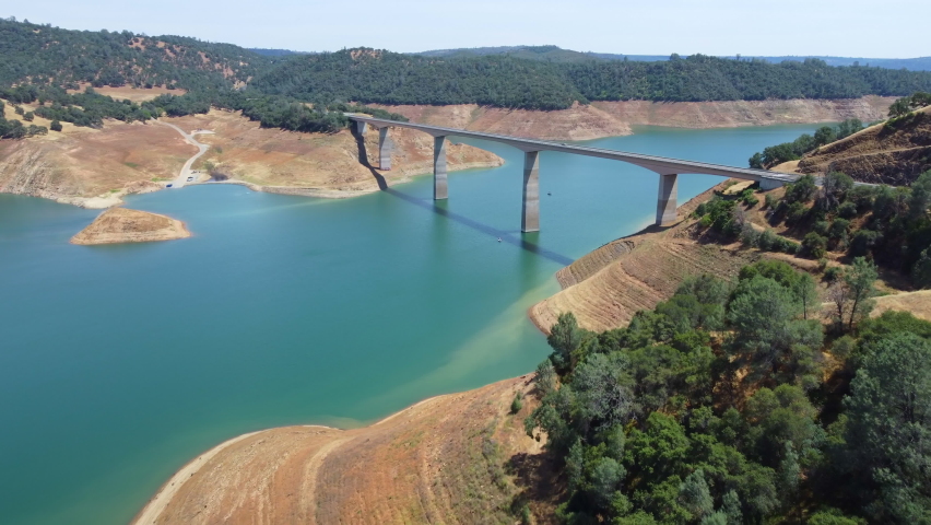 Aerial fly Calaveras County, California, now submerged beneath a reservoir named New Melones Lake. Flight over a large bridge over a reservoir in California National Park