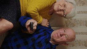 senior couple watching something funny on TV at home medium shot indoor vertical video senior people concept. High quality 4k footage - Powered by Shutterstock - Get 15% off with code: PIKWIZARD15
