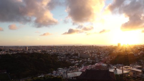 NAHA, OKINAWA, JAPAN - AUG 2021 : Aerial view of Naha city in sunset. Cityscape of downtown area. High angle wide view, time lapse shot dusk to night. Summer holiday, vacation and travel concept video