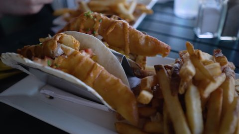 Close up of fish tacos and french fries on a plate at a restaurant