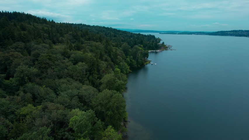 Fly over view of the sloping mountain with Dark Green forest touching the Waters of the Lake Washington during morning hours