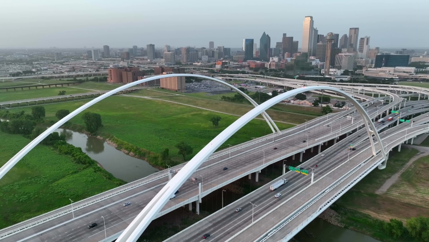 Arch and span of Margaret McDermott Bridge and Dallas skyline. I-30 traffic on interstate loop in Texas.