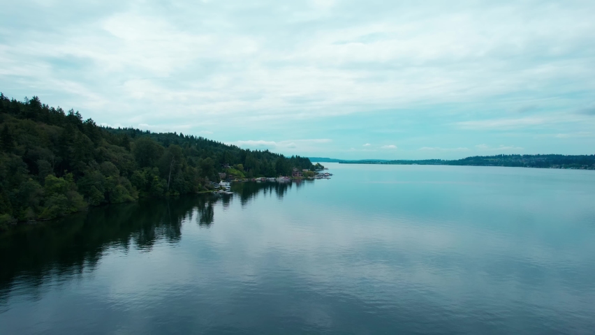 Flight over the calm morning waters of Lake Washington with amazing reflections of Sky and shore trees