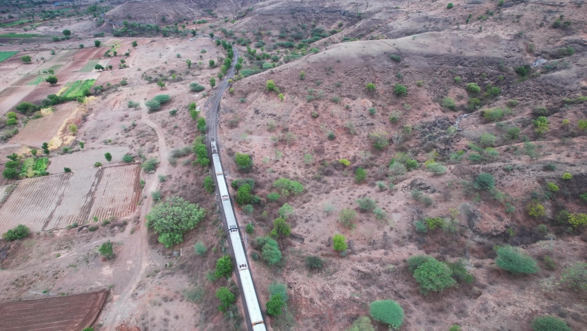 Aerial view of a passenger train of the Indian Railways hauled by an electric WCAM-3 locomotive at Shindawane near Pune India.