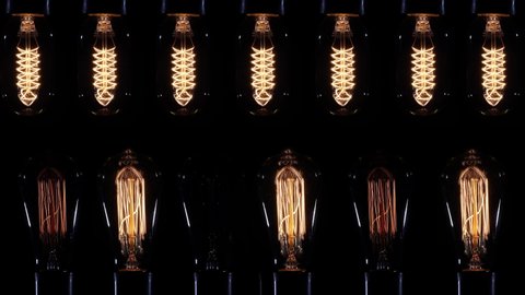 Vintage light bulb pulsing light in the darkness. A lot of tungsten lamp bulbs creating blinking pulsing background.