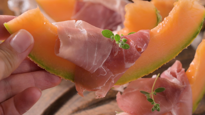 Italian prosciutto crudo with melons. Slices of traditional ham wrapped around melons. Tasty appetizer. Food background. Close up. Snack for wine for an aperitif