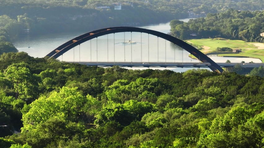 Rising up to reveal Pennybacker 360 bridge in Austin, Texas over Lake Austin during hazy summer morning, zoomed in aerial drone 2022 in 4k Royalty-Free Stock Footage #1091774105