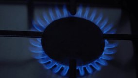 The stove is on fire. The top burner is lit with a blue flame for cooking of natural gas, close-up view.
Gas is switching on, apearing blue flame. Gas stove on the black background.