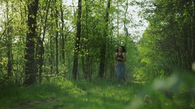 Slow motion video of a Caucasian woman jogging in the woods. Beautiful girl running on the path in the park, active lifestyle and outdoor sports.