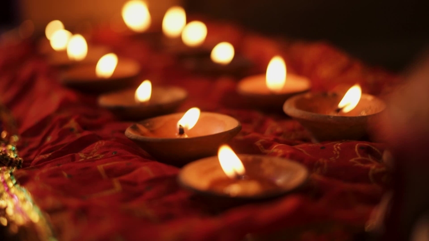 Diwali Diya oil lamps placed on a table among with other glowing Diya lamps with bokeh in background. Hindu background, Decorative Glitter Diya lamps.  Royalty-Free Stock Footage #1091777025