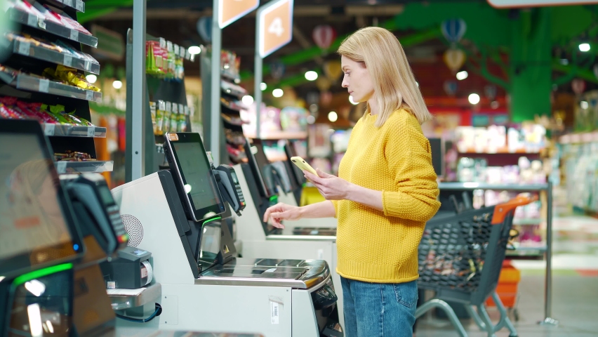female buyer using a self-service cashier checkout in a supermarket. Customer scanning produce items using at grocery store self serve cash register. cashier terminal woman pay for products online Royalty-Free Stock Footage #1091778701