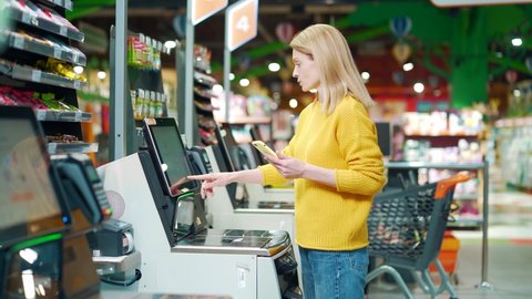 female buyer using a self-service cashier checkout in a supermarket. Customer scanning produce items using at grocery store self serve cash register. cashier terminal woman pay for products online, videoclip de stoc