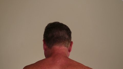 Both hands of a shirtless adult white caucasian man massaging his scalp with both of his hands close-up. Rear view of a shirtless white male massaging his head with the fingers of both of his hands.