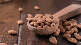 Scatters almonds on a wooden background. Almond nuts., ideal for social networks and smartphones. High quality FullHD footage