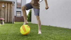 Close up 4k video of boys legs playing with ball on green grass at summer holidays