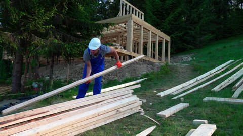 Construction worker builds a house. Caucasian Contractor and the Wooden House Frame.Energy efficient frame house. New framing construction of a house. Construction crew working,  commercial apartment