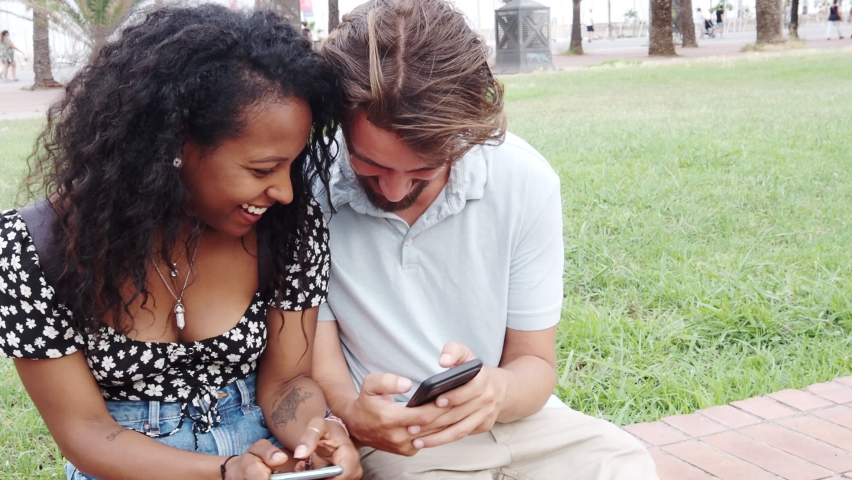 Multi-ethnic heterosexual young couple looking at a mobile phone in the city.Social networks, couple on vacation | Shutterstock HD Video #1091791665