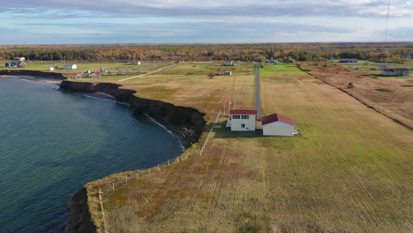 Aerial view over a residential property close to eroding coastal cliffs on the Acadian Peninsula in Caraquet, New Brunswick, Canada. With copy space. Royalty-Free Stock Footage #1091797741