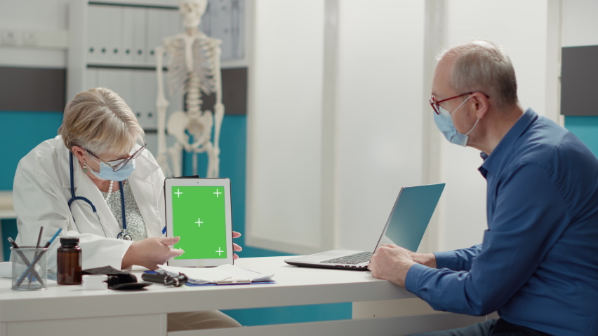 Physician showing digital tablet with greenscreen to old man in medical office during coronavirus pandemic. Blank isolated copyspace and mockup template with chroma key background. | Shutterstock HD Video #1091797841