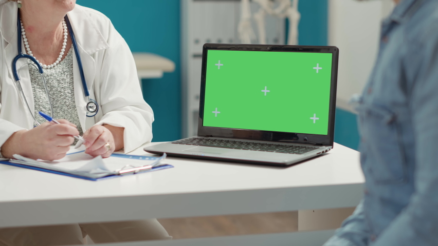Young adult and medic using laptop with greenscreen at checkup visit, looking at isolated mockup template with blank copy space and chromakey background on display. Computer screen. | Shutterstock HD Video #1091797857