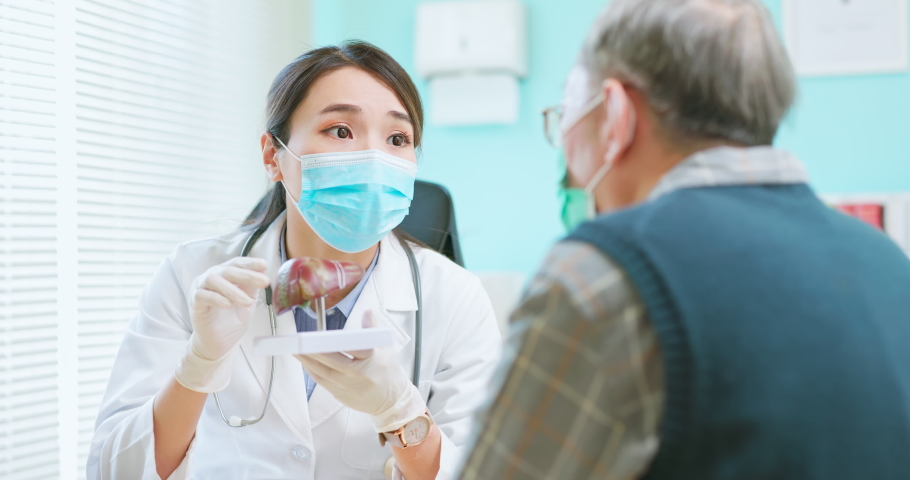Asian female doctor wearing face mask is showing liver model and explaining to elder senior man patient in hospital | Shutterstock HD Video #1091799527