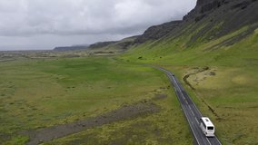 Tour bus driving through the mountains of Iceland with drone video following.