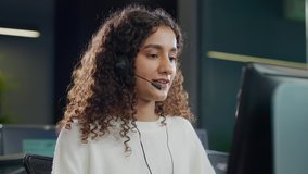 A modern attractive smiling young Indian Asian call center or customer care support curly haired female or woman employee in headset mic busy talking or interacting with client in a corporate office. - Powered by Shutterstock - Get 15% off with code: PIKWIZARD15