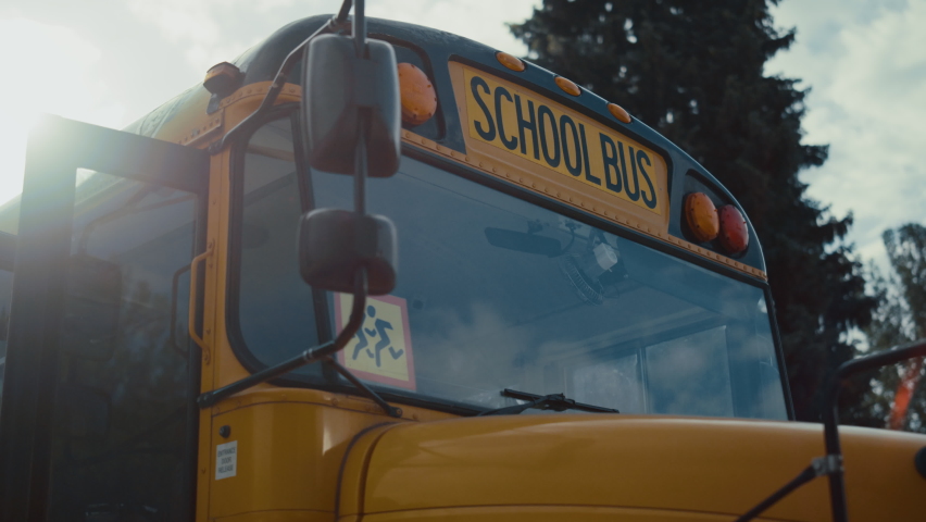 Front view academic bus window with warning sign yellow red headlights close up. School vehicle parking on street sunny morning. Empty schoolbus without children open door for pupils boarding. | Shutterstock HD Video #1091809637
