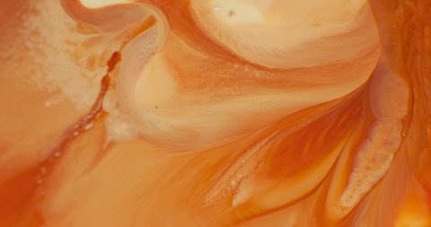 Orange paint abstraction in motion, close up. Bright light orange color abstract liquid patterns blend, flow background. Colorful orange shades ink wallpaper. Beautiful yellow-red 4k vertical footage