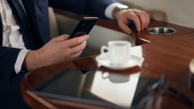 Man hands using cellphone on business trip. Wealthy businessman swiping phone browsing internet in private jet. Successful unknown passenger checking email messaging online. Business lifestyle concept - Powered by Shutterstock - Get 15% off with code: PIKWIZARD15