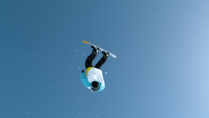 SLOW MOTION: Fearless young snowboarder does a backflip after jumping off a massive kicker. Athletic male tourist snowboarding in the Chinese mountains does a flip while riding in the snowboard park. - Powered by Shutterstock - Get 15% off with code: PIKWIZARD15