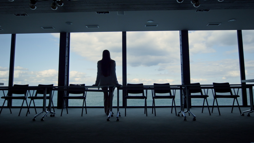 Woman silhouette enjoying break in conference room. Calm beautiful sea view. Unrecognized businesswoman ceo thinking life problems dreaming in office room alone. Peaceful manager going back to work